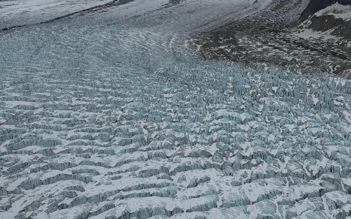 Crevasses on a glacier seen past the wing of a small plane