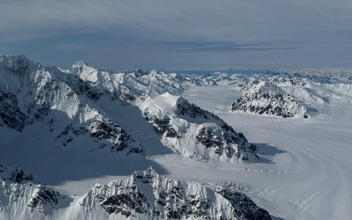 The summit of Denali standing above a layer of cloud, seen from a small aircraft