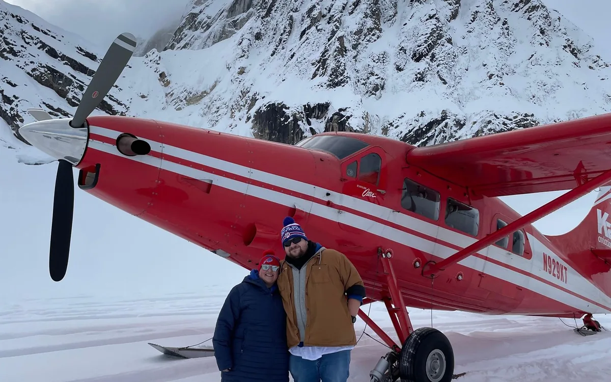 Walkers on the snow of a glacier in the Alaska Range beside a parked ski plane