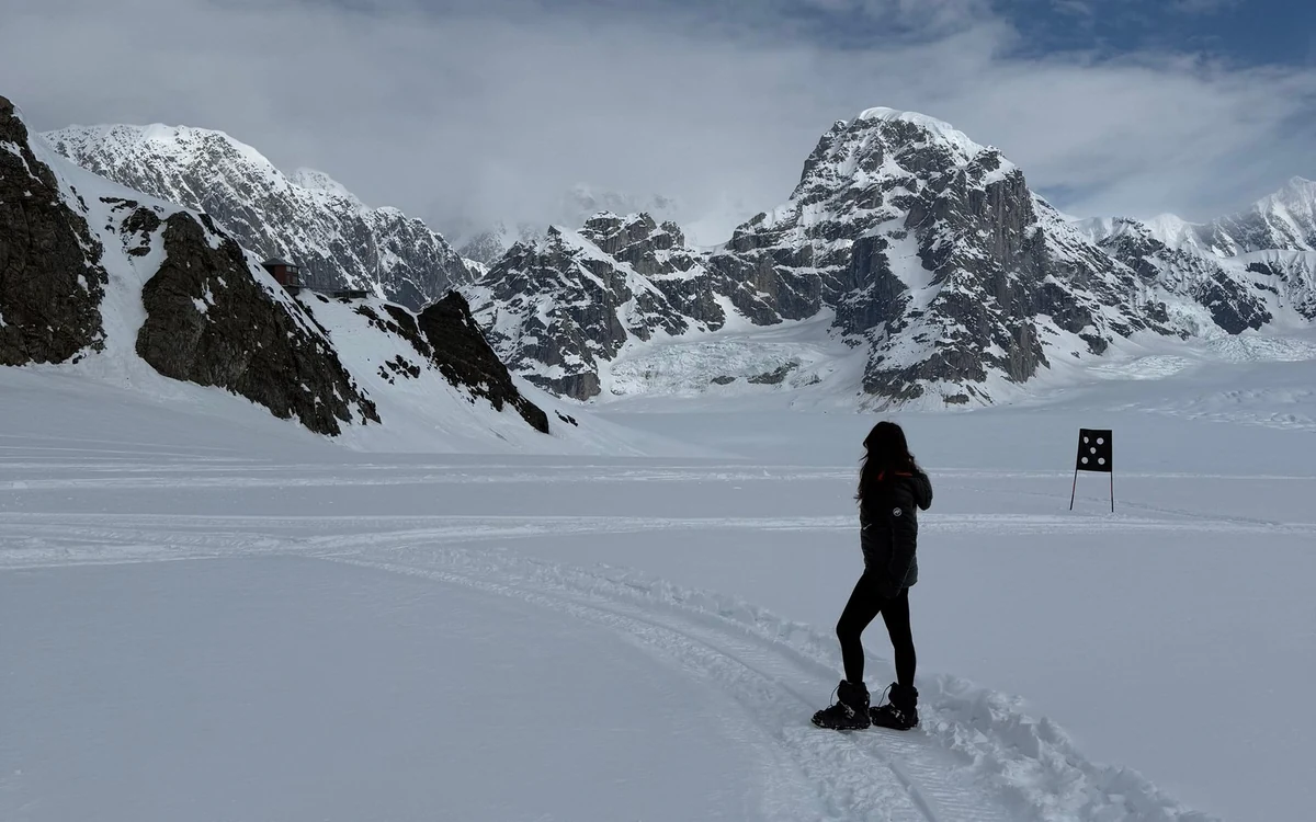 People walking on packed snow beside a ski plane high in the Alaska Range