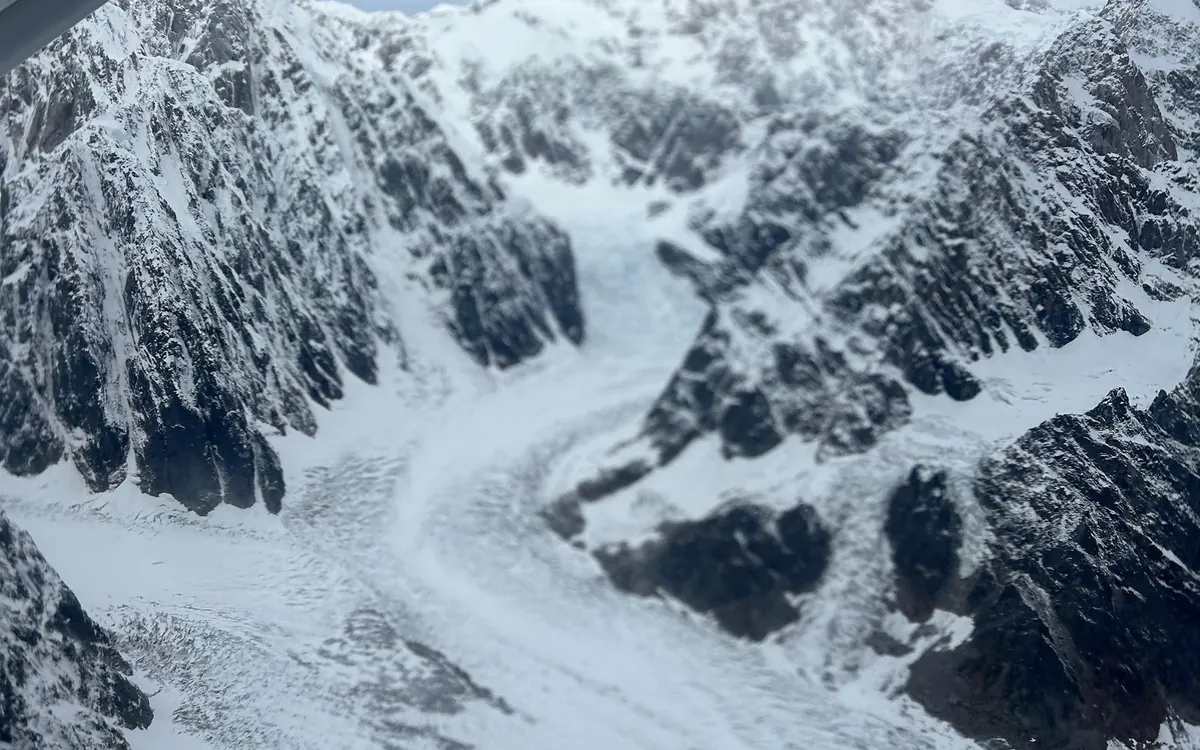 A glacier and its icefall seen from the window of a small plane with the wing strut in the corner